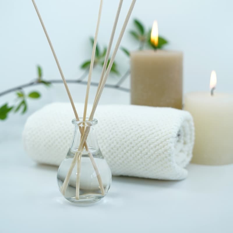 A rolled towel, a candle, and a reed diffuser